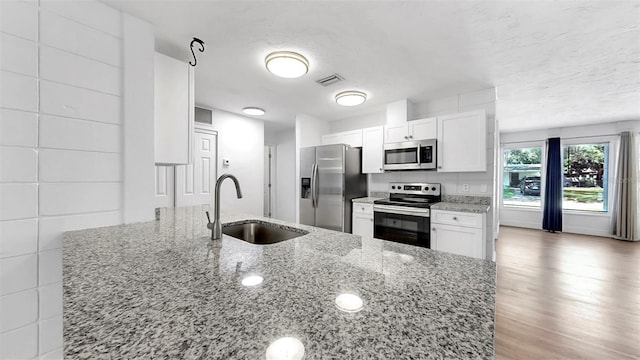 4455 Emerald Ridge Dr, Sarasota, FL 34233 - kitchen featuring appliances with stainless steel finishes, white cabinetry, light stone counters, and a textured ceiling