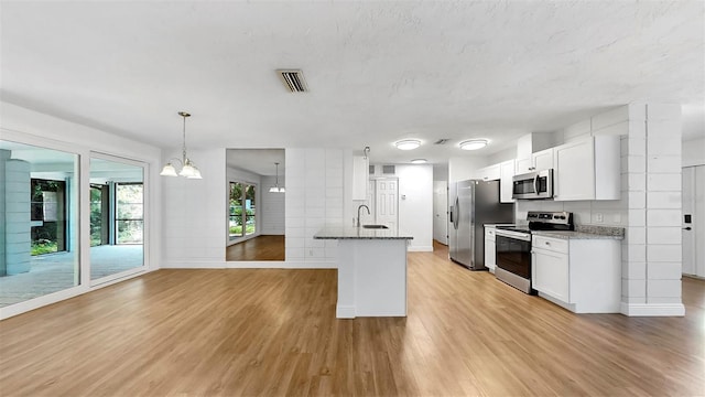 4455 Emerald Ridge Dr, Sarasota, FL 34233 - kitchen featuring appliances with stainless steel finishes, light wood-style flooring, dark stone countertops, white cabinetry, and a chandelier