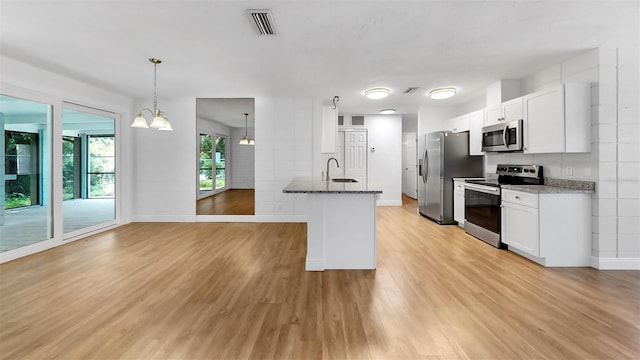 4455 Emerald Ridge Dr, Sarasota, FL 34233 - kitchen with stainless steel appliances, light wood-style flooring, dark stone countertops, and white cabinetry