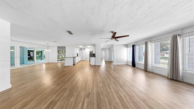 4455 Emerald Ridge Dr, Sarasota, FL 34233 - unfurnished living room with ceiling fan, healthy amount of natural light, light wood-style floors, and a textured ceiling