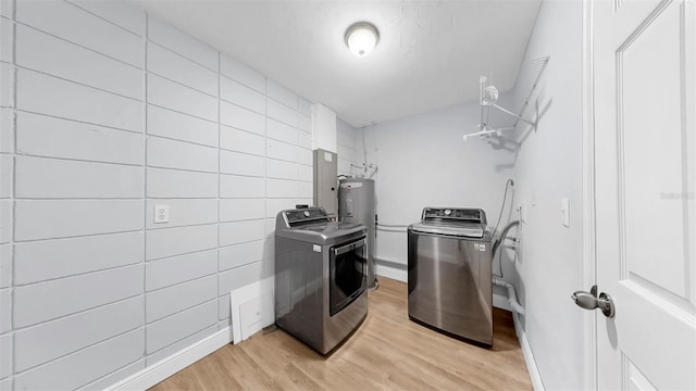 4455 Emerald Ridge Dr, Sarasota, FL 34233 - laundry area featuring washing machine and clothes dryer, light wood-style flooring, water heater, tile walls, and electric panel