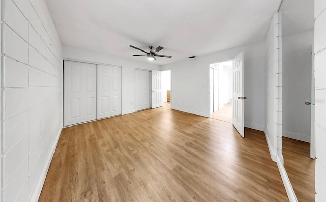 4455 Emerald Ridge Dr, Sarasota, FL 34233 - unfurnished bedroom featuring multiple closets, light wood finished floors, and ceiling fan
