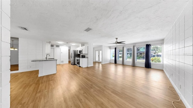 4455 Emerald Ridge Dr, Sarasota, FL 34233 - unfurnished living room featuring a ceiling fan, light wood-style floors, and a textured ceiling