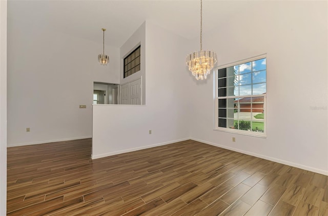 1144 Hoover St, Nokomis, FL 34275 - unfurnished room with a chandelier, a towering ceiling, and wood finished floors