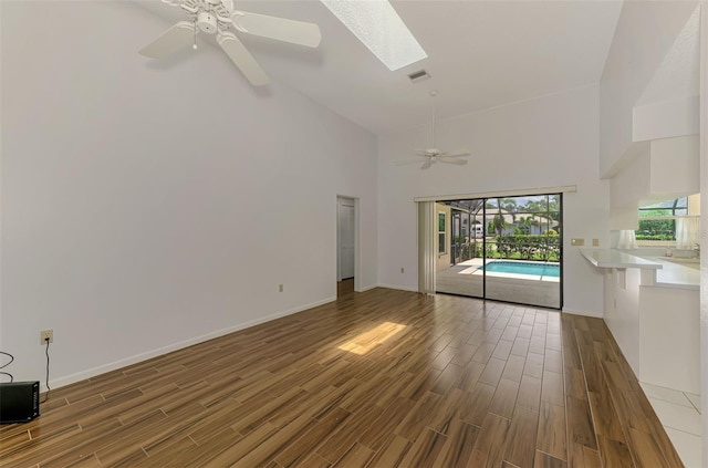 1144 Hoover St, Nokomis, FL 34275 - unfurnished living room with high vaulted ceiling, ceiling fan, wood finished floors, and a skylight