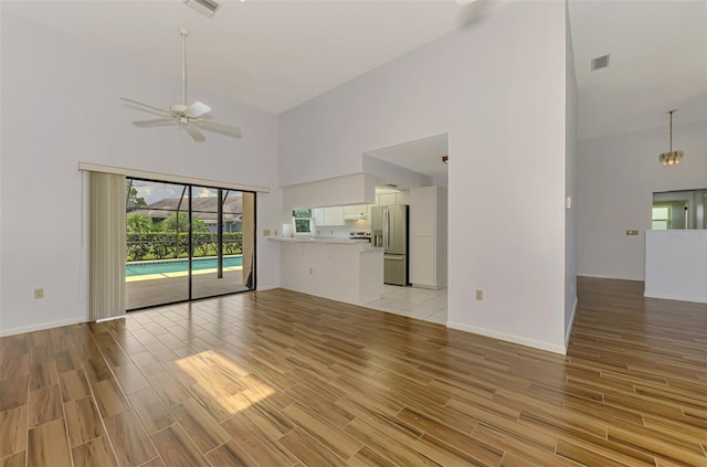 1144 Hoover St, Nokomis, FL 34275 - unfurnished living room with high vaulted ceiling, light wood-style flooring, and a ceiling fan