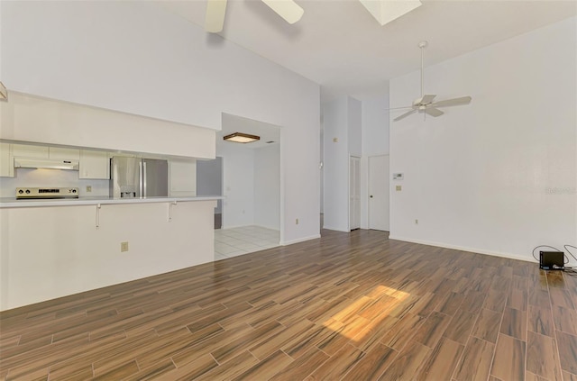 1144 Hoover St, Nokomis, FL 34275 - unfurnished living room with ceiling fan, light wood-type flooring, high vaulted ceiling, and a skylight