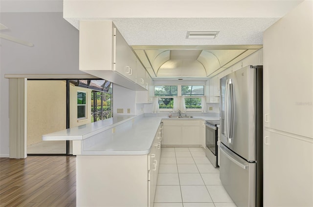 1144 Hoover St, Nokomis, FL 34275 - kitchen with appliances with stainless steel finishes, a peninsula, light countertops, white cabinetry, and a kitchen breakfast bar