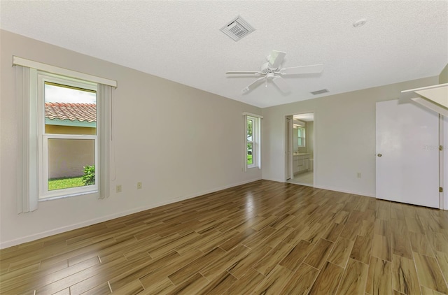 1144 Hoover St, Nokomis, FL 34275 - unfurnished bedroom featuring light wood-type flooring, a textured ceiling, connected bathroom, and a ceiling fan