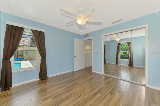 1144 Hoover St, Nokomis, FL 34275 - unfurnished bedroom featuring wood finished floors, a ceiling fan, a closet, and a textured ceiling