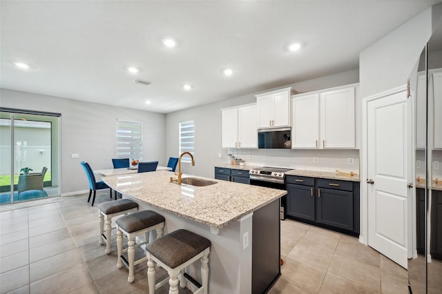 4405 Weathered Moss Gln, Palmetto, FL 34221 - kitchen with stainless steel appliances, a kitchen breakfast bar, an island with sink, white cabinetry, and backsplash