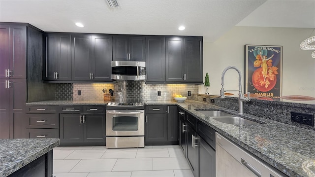 1921 Monte Carlo Dr Unit 302, Sarasota, FL 34231 - kitchen with appliances with stainless steel finishes, dark stone counters, decorative backsplash, light tile patterned floors, and dark cabinets