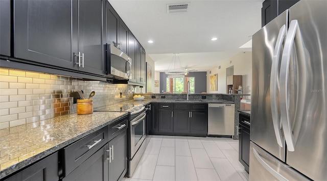 1921 Monte Carlo Dr Unit 302, Sarasota, FL 34231 - kitchen with appliances with stainless steel finishes, light stone counters, light tile patterned floors, decorative backsplash, and a peninsula