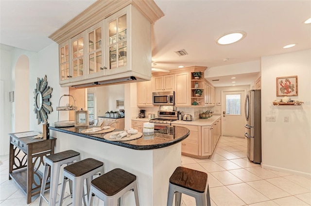 160 Coolidge Dr, Sarasota, FL 34236 - kitchen with appliances with stainless steel finishes, light tile patterned flooring, a breakfast bar, arched walkways, and recessed lighting