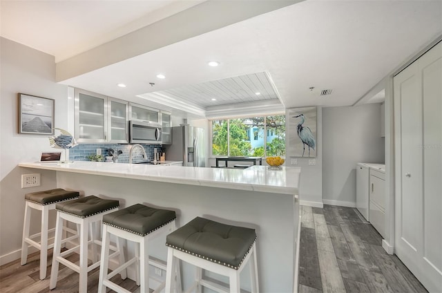 1740 Alderman St Unit 7, Sarasota, FL 34236 - kitchen featuring washer and dryer, stainless steel appliances, a raised ceiling, a peninsula, and light countertops