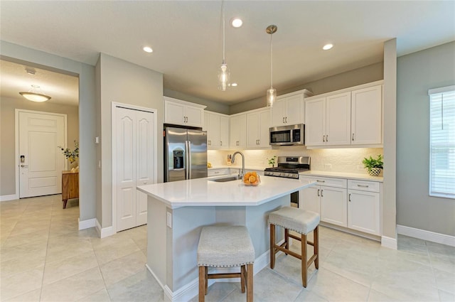 11685 Great Brook Ln, Parrish, FL 34219 - kitchen with stainless steel appliances, tasteful backsplash, light countertops, white cabinets, and an island with sink