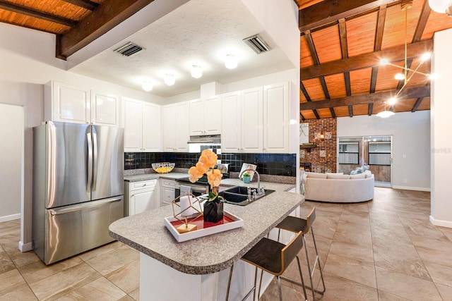 4232 Pandora Rd, Venice, FL 34293 - kitchen with appliances with stainless steel finishes, tasteful backsplash, white cabinetry, a wood ceiling with exposed beams, and a kitchen bar
