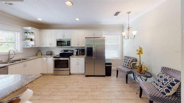 152 Coolidge Dr, Sarasota, FL 34236 - kitchen featuring appliances with stainless steel finishes, white cabinets, ornamental molding, light stone counters, and light wood-style floors