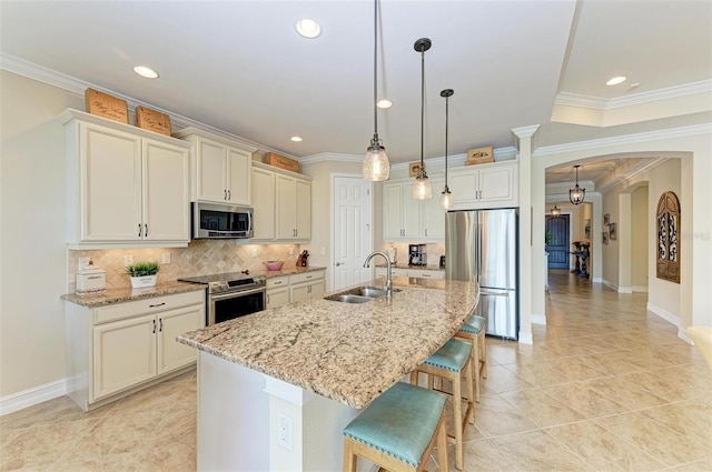 138 Toscavilla Blvd, Nokomis, FL 34275 - kitchen with appliances with stainless steel finishes, arched walkways, a breakfast bar area, ornamental molding, and backsplash