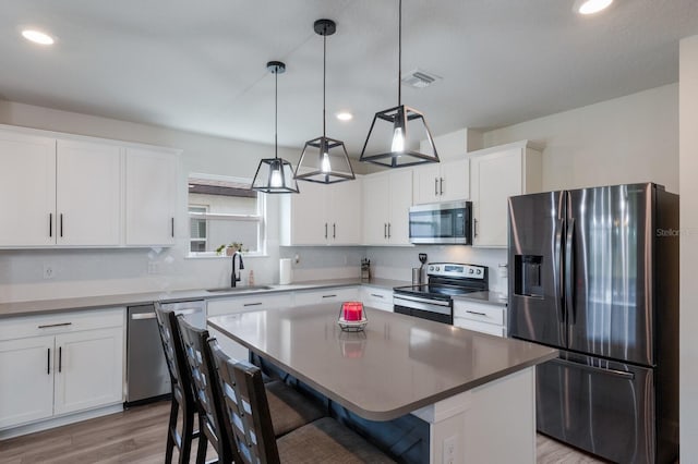 8985 Royal River Cir, Parrish, FL 34219 - kitchen featuring stainless steel appliances, light wood-style flooring, white cabinetry, recessed lighting, and a kitchen bar