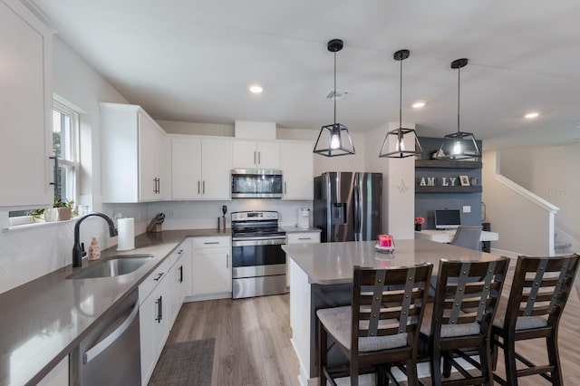 8985 Royal River Cir, Parrish, FL 34219 - kitchen featuring appliances with stainless steel finishes, decorative backsplash, a breakfast bar area, light wood finished floors, and white cabinets
