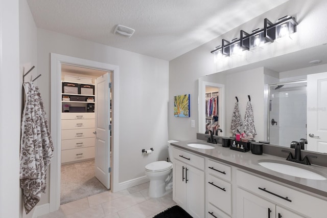 8985 Royal River Cir, Parrish, FL 34219 - bathroom featuring a spacious closet, double vanity, a shower stall, tile patterned flooring, and a textured ceiling