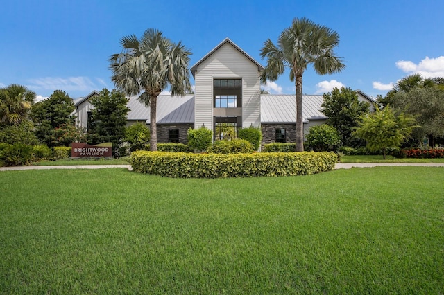 8985 Royal River Cir, Parrish, FL 34219 - modern home with a standing seam roof, a front lawn, stone siding, and a metal roof