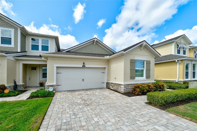 3681 Divot Ln, Sarasota, FL 34232 - view of front facade featuring decorative driveway, stone siding, an attached garage, and stucco siding