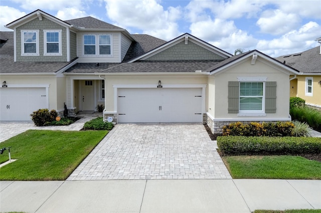 3681 Divot Ln, Sarasota, FL 34232 - view of front of house featuring decorative driveway, a shingled roof, a front yard, stone siding, and a garage