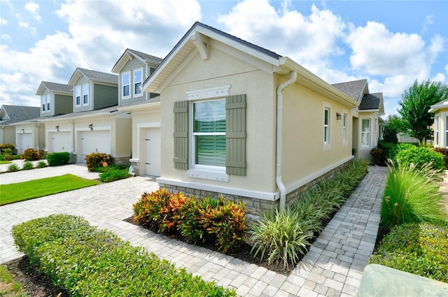 3681 Divot Ln, Sarasota, FL 34232 - view of front facade with decorative driveway, stone siding, stucco siding, an attached garage, and roof with shingles