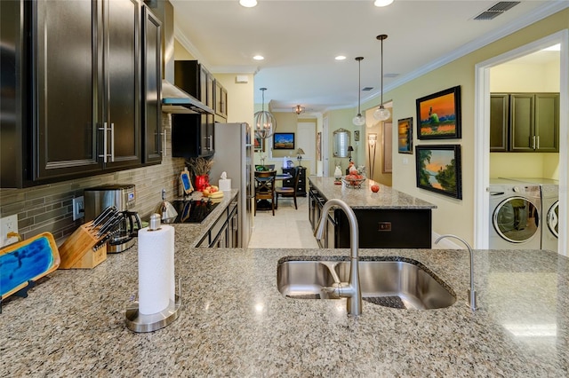 3681 Divot Ln, Sarasota, FL 34232 - kitchen with washer and dryer, freestanding refrigerator, light stone countertops, ornamental molding, and tasteful backsplash