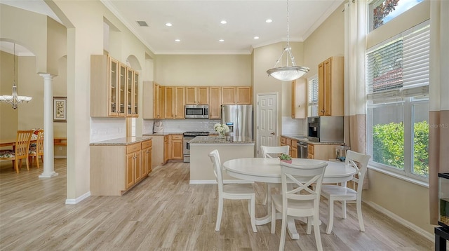 7717 US Open Loop, Lakewood Ranch, FL 34202 - kitchen featuring stainless steel appliances, a towering ceiling, a kitchen island, light brown cabinetry, and backsplash