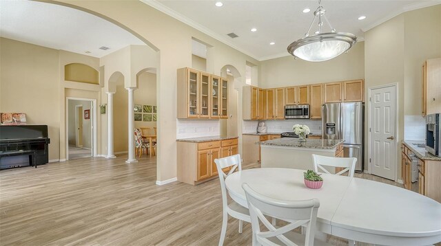 7717 US Open Loop, Lakewood Ranch, FL 34202 - kitchen with appliances with stainless steel finishes, a towering ceiling, ornamental molding, a center island, and tasteful backsplash