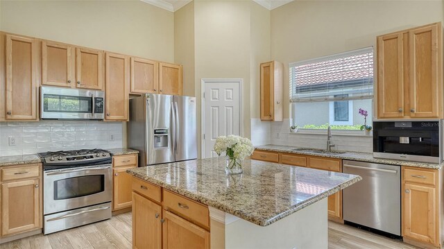 7717 US Open Loop, Lakewood Ranch, FL 34202 - kitchen featuring stainless steel appliances, ornamental molding, light brown cabinetry, a kitchen island, and backsplash