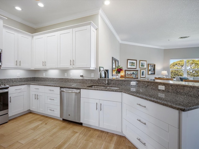 7840 34th Ave W Unit 303, Bradenton, FL 34209 - kitchen with appliances with stainless steel finishes, a peninsula, white cabinets, light wood-style flooring, and dark stone counters