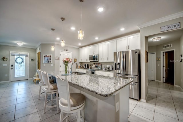 640 Encarnacion St, Punta Gorda, FL 33983 - kitchen with stainless steel appliances, ornamental molding, light tile patterned floors, white cabinets, and an island with sink