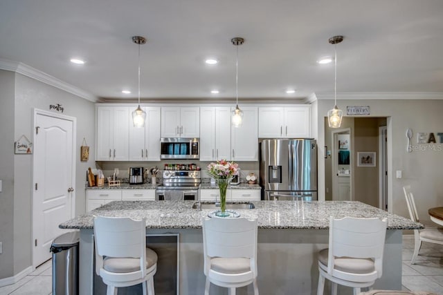 640 Encarnacion St, Punta Gorda, FL 33983 - kitchen featuring stainless steel appliances, white cabinets, ornamental molding, a kitchen breakfast bar, and a kitchen island with sink