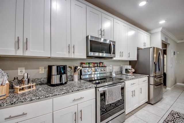640 Encarnacion St, Punta Gorda, FL 33983 - kitchen with stainless steel appliances, ornamental molding, white cabinets, light tile patterned flooring, and light stone countertops
