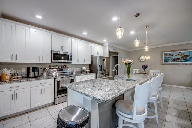 640 Encarnacion St, Punta Gorda, FL 33983 - kitchen with stainless steel appliances, ornamental molding, light tile patterned floors, a kitchen island with sink, and white cabinetry