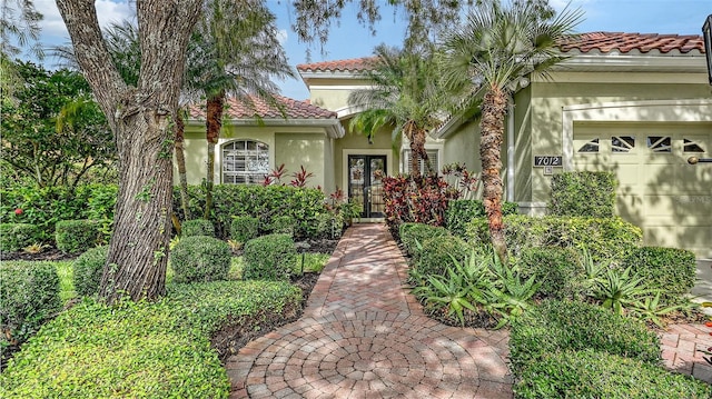 7012 Treymore Ct, Sarasota, FL 34243 - mediterranean / spanish house featuring a tile roof, stucco siding, an attached garage, and french doors