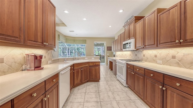 7012 Treymore Ct, Sarasota, FL 34243 - kitchen with white appliances, light countertops, tasteful backsplash, brown cabinetry, and recessed lighting