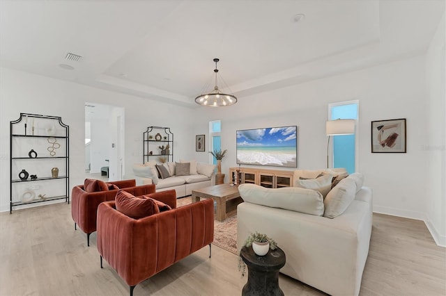 6028 Red Mangrove Ln, Bradenton, FL 34210 - living room featuring a raised ceiling, light wood-style flooring, and a chandelier