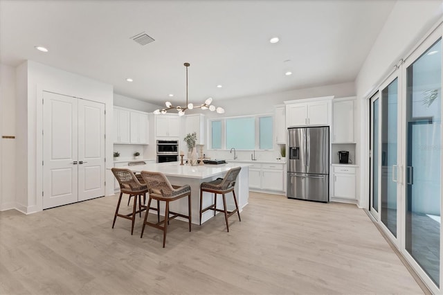 6028 Red Mangrove Ln, Bradenton, FL 34210 - kitchen with appliances with stainless steel finishes, a chandelier, white cabinets, light countertops, and a kitchen breakfast bar