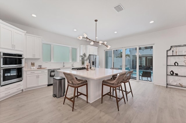 6028 Red Mangrove Ln, Bradenton, FL 34210 - kitchen featuring appliances with stainless steel finishes, light wood-style flooring, a kitchen island, a breakfast bar area, and recessed lighting
