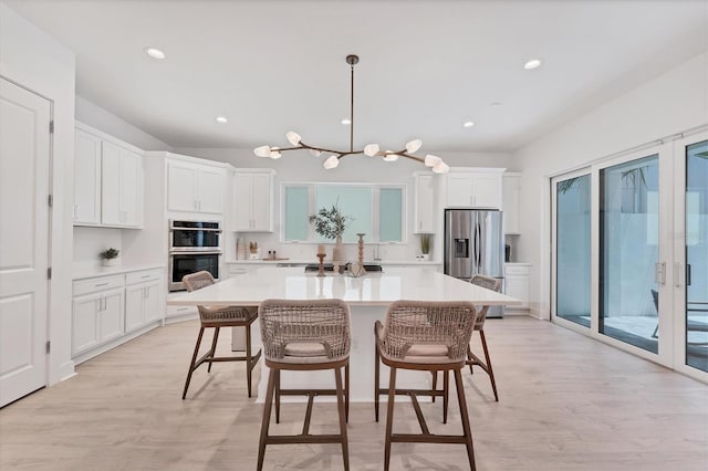 6028 Red Mangrove Ln, Bradenton, FL 34210 - kitchen featuring appliances with stainless steel finishes, a center island, white cabinetry, light countertops, and a kitchen breakfast bar