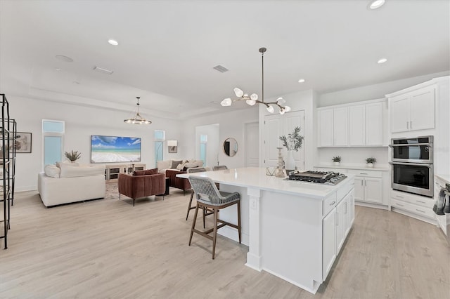 6028 Red Mangrove Ln, Bradenton, FL 34210 - kitchen with appliances with stainless steel finishes, open floor plan, a kitchen island, light countertops, and light wood-style floors