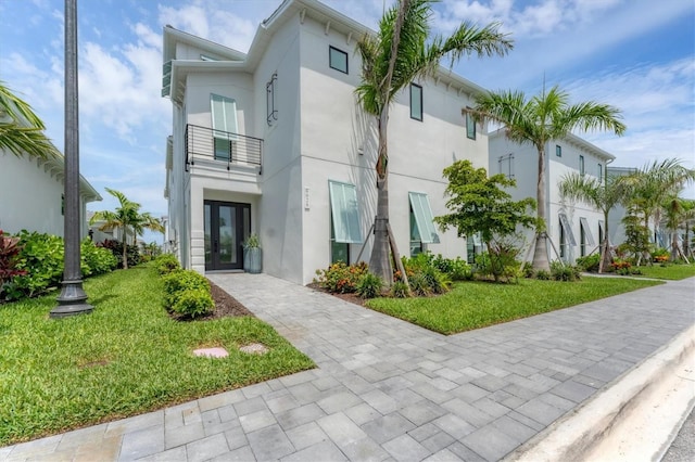 6028 Red Mangrove Ln, Bradenton, FL 34210 - view of front of property with a balcony, stucco siding, a front lawn, and french doors