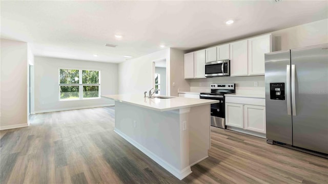 12071 Mountain Island Trl, Parrish, FL 34219 - kitchen featuring stainless steel appliances, wood finished floors, an island with sink, light countertops, and white cabinets