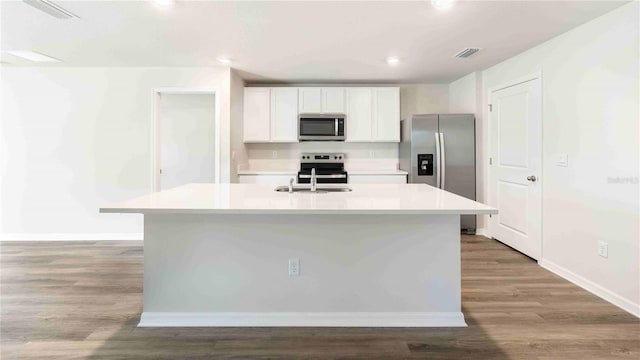 12071 Mountain Island Trl, Parrish, FL 34219 - kitchen featuring stainless steel appliances, white cabinets, light countertops, a kitchen island with sink, and wood finished floors