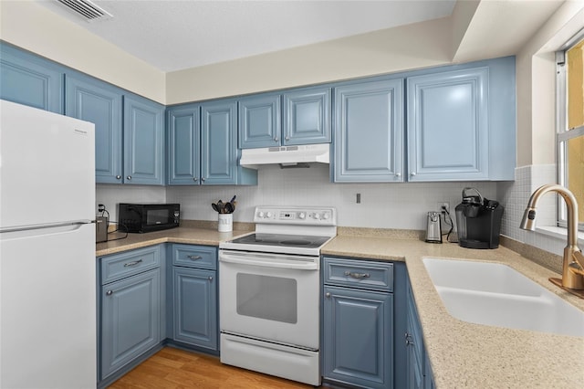 409 Archibald Ave, Sarasota, FL 34243 - kitchen with white appliances, blue cabinets, under cabinet range hood, light countertops, and tasteful backsplash